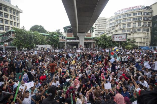 Protesters gather under a highway bridge.