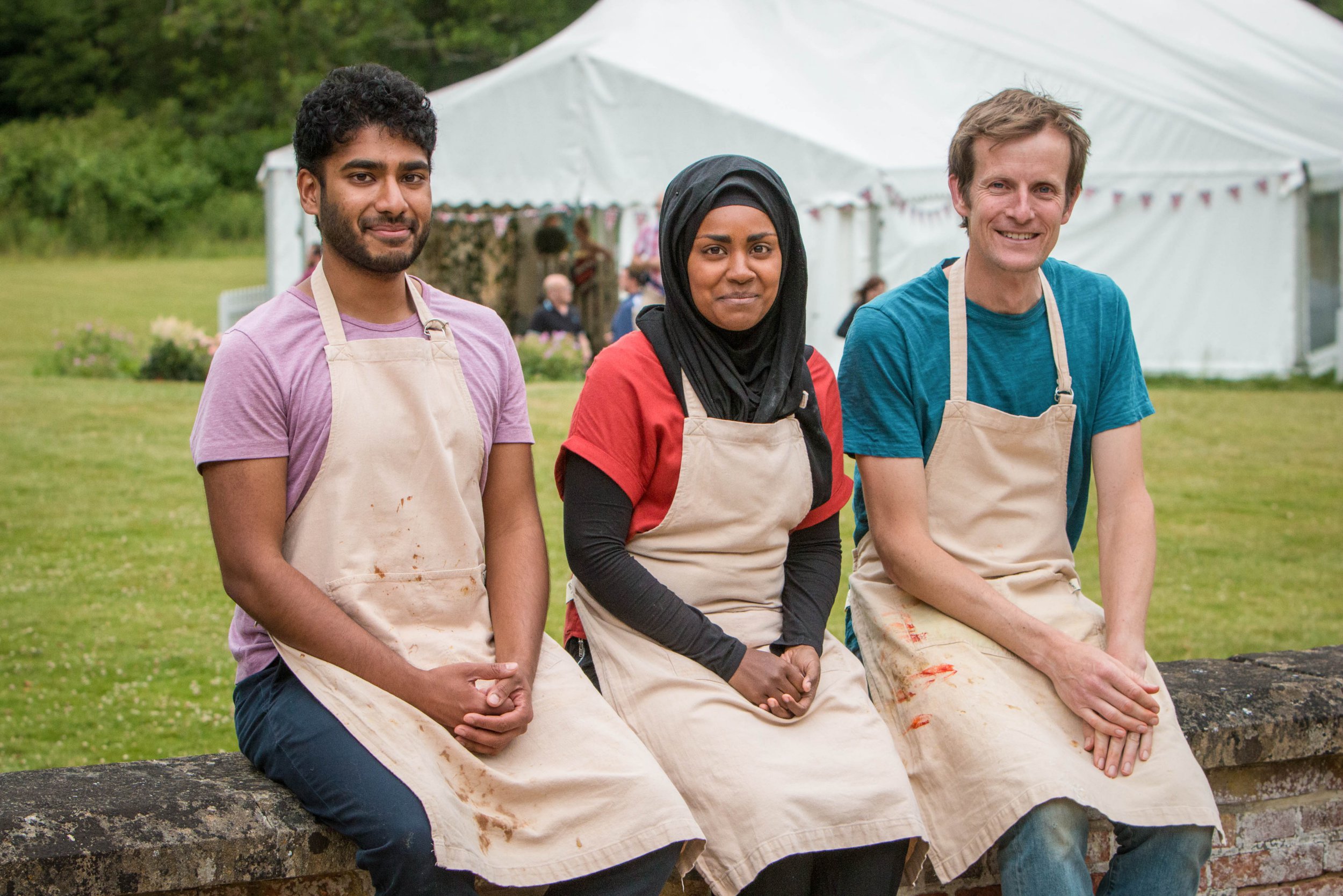 The Great British Bake Off finalists Tamal Ray, Nadiya Hussain and Ian Cumming sat on a wall outside the famous white tent